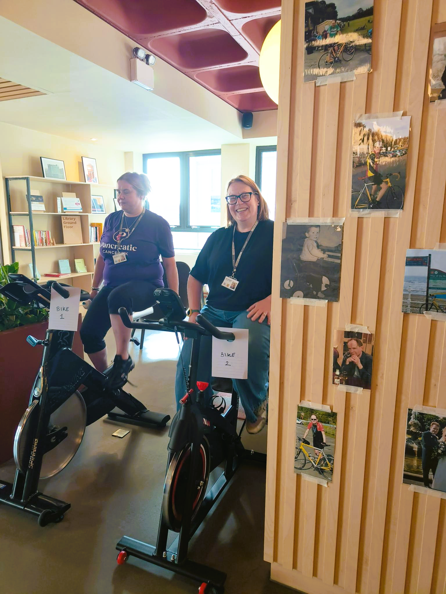 Two SYHA employees on stationary bikes in our Rockingham Street office.