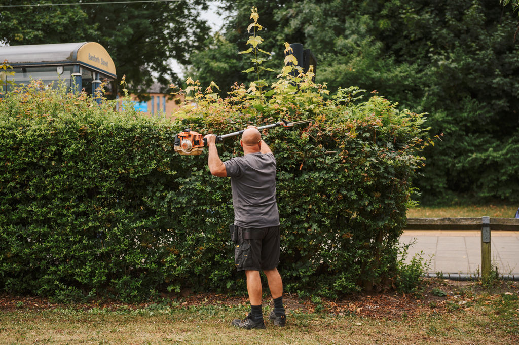 A photo of an SYHA employee strimming a hedge.