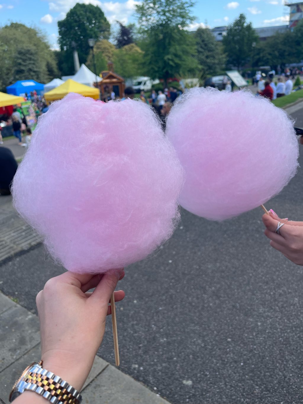 Two hands holding some candyfloss at a fair.