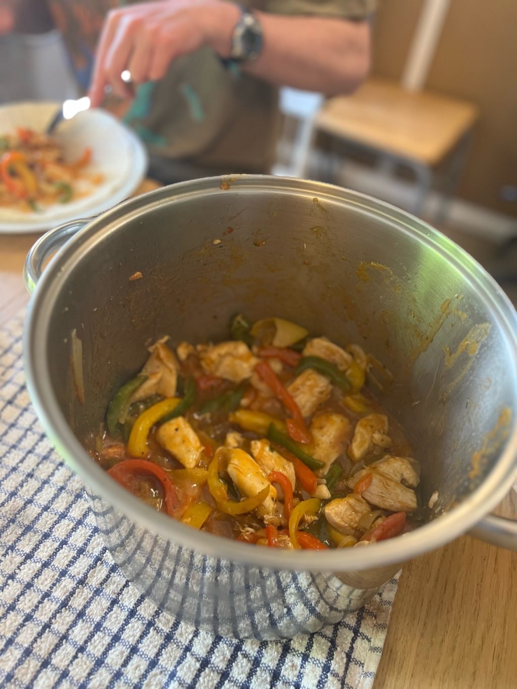 A pot of chicken and vegetables at the dinner table.