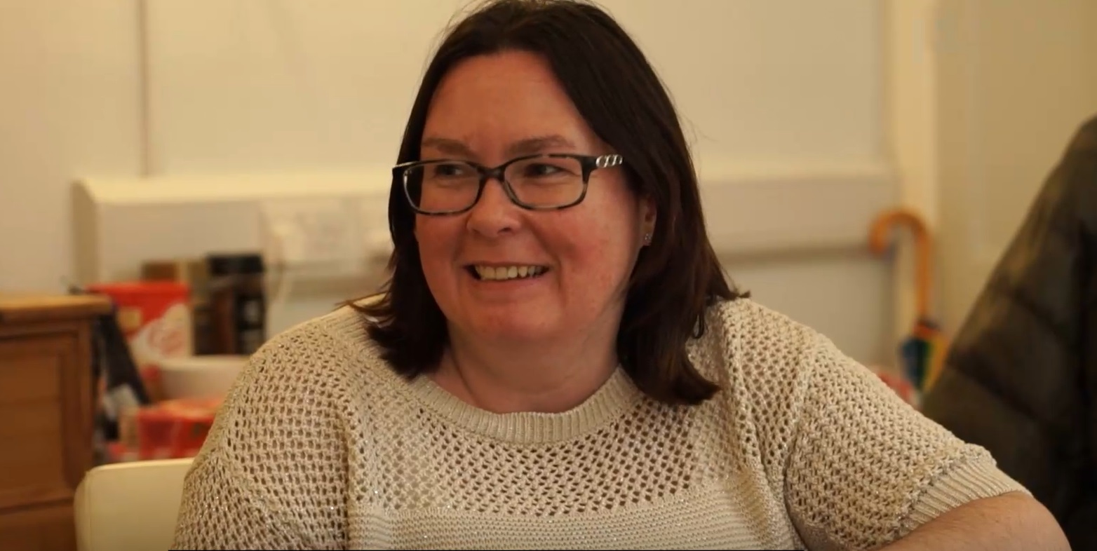 A photo of Lisa. She's wearing a white top and smiling to someone off-camera.