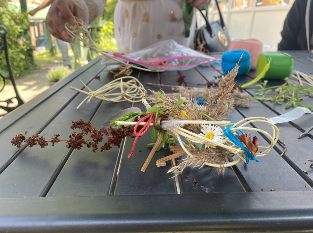 A feather, flowers and dried plants tied together.